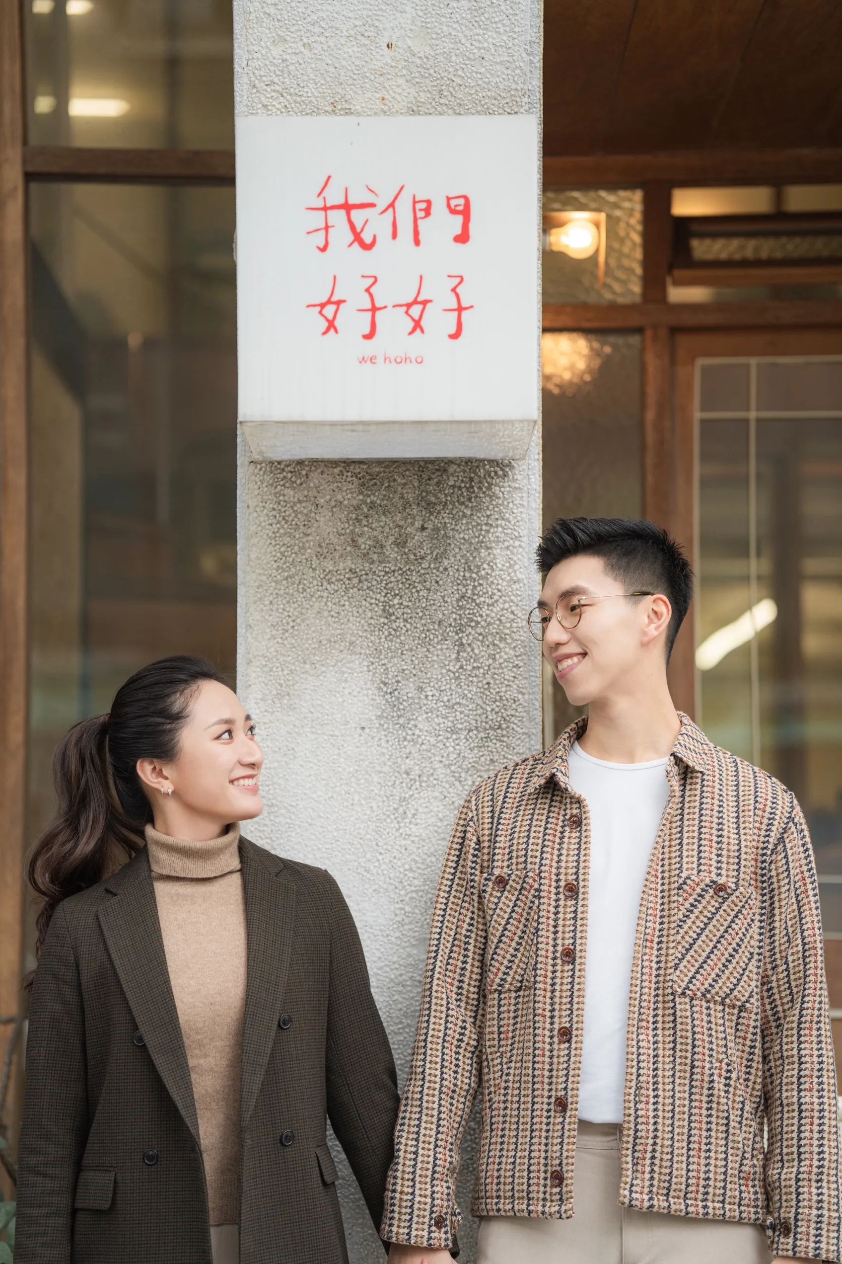 Gino and Tiffany holding hands in front of a Taiwanese cafe, smiling at each other.